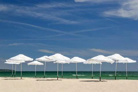 Umbrellas at an empty beach on a sunny day Stock Photos