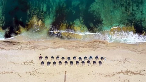 Umbrellas lined up on the sandy beach by the turquoise sea 스톡 동영상 203816803