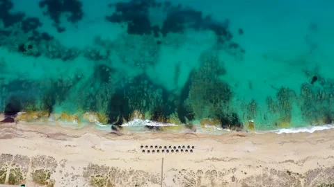 Umbrellas lined up on the sandy beach by the turquoise sea Stock-Footage 203820692