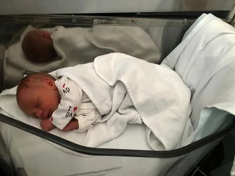 Un bebé recién nacido yace en una cama móvil en un hospital de maternidad Stock Photos