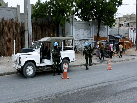 UN peacekeepers stand in formation around their vehicle Stock Footage