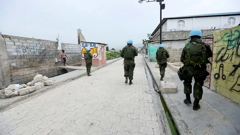 UN peacekeepers walk in formation down an empty street Stock Footage