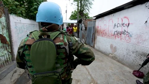 A UN soldier directs a civilian to expose his waist to check for hidden weapons Stock Footage