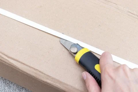 Unboxing a cardboard box with new furniture with construction or office knife Stock Photos
