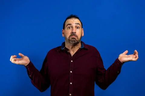Uncertain man throwing up hands and looking at camera. Young guy doubting. Co Stock Photos