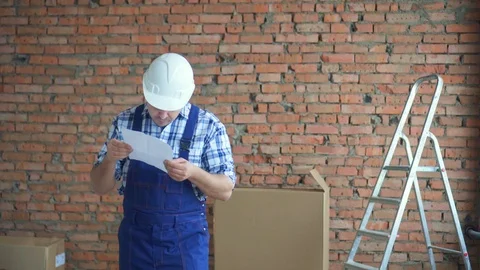 An uncomprehending male builder with a building plan in his hands Stock-Footage 99537098