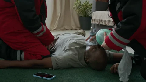 Unconscious Man Lying on Floor while Paramedics Doing CPR and Using Oxygen Mask Stock Footage 293677046