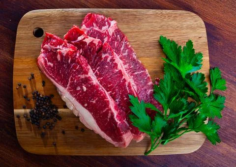 Uncooked beef marbled steak served with pepper and parley on the table Fotos de archivo