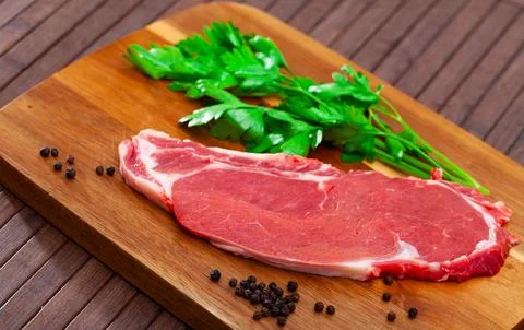 Uncooked beef marbled steak served with pepper and parley on the table Fotos de archivo