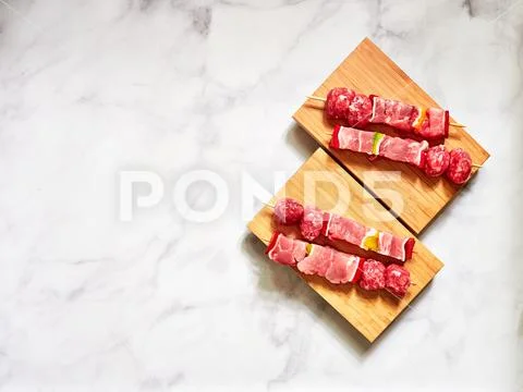 Uncooked beef skewers top down view isolated over a wood plank Stock Photos