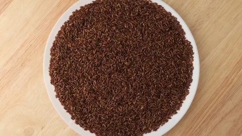 Uncooked brown rice rotating on a plate Stock Footage 342437054