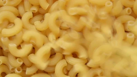 Uncooked elbow macaroni being poured into a heap of pasta full screen Stock Footage 193993126