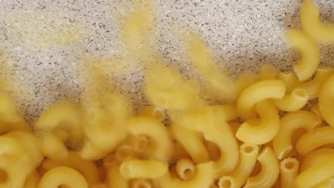 Uncooked elbow macaroni slowly being poured and filling up screen bottom to top Stock Footage 193993898