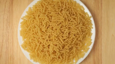 Uncooked fusilli pasta rotating on a plate Видео 341281135