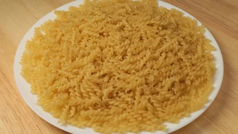 Uncooked fusilli pasta rotating on a plate Stock Footage 343435553