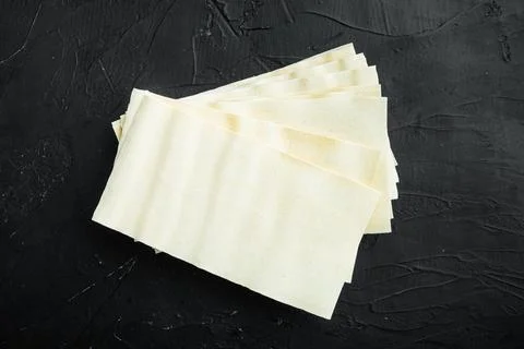 Uncooked lasagna sheets, on black stone background, top view, flat lay Stock Photos
