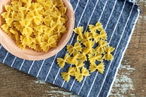 Uncooked mini farfalle pasta on rustic background Stock Photos