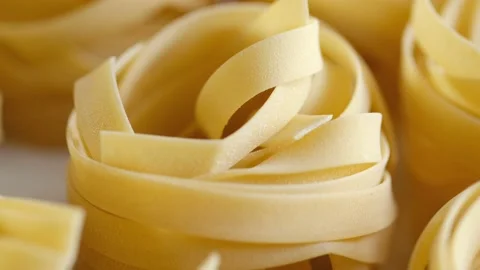 Uncooked noodle nest . Slow motion video.slow motion pasta dry tagliatelle spin Stock Footage 169061687