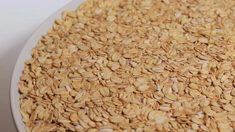 Uncooked Oat Flakes Rotating on White Plate Stock Footage 224439641