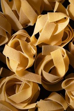 Uncooked pasta nests arranged in pattern, black background, raw food Foto stock