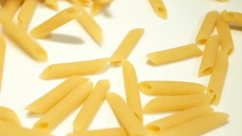 Uncooked penne pasta falling on white surface slow motion,kitchen food Stock Footage 140670801