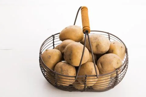 Uncooked potatoes in wire basket Stock Photos