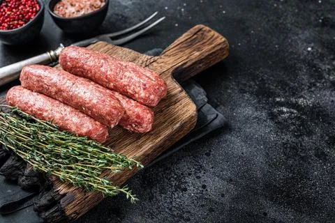 Uncooked Raw beef and lamb meat kebabs sausages on a wooden board. Black Stock Photos
