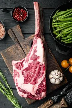 Uncooked raw beef red meat marbled with bone in, with grill ingredients, on b Stock Photos