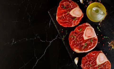 Uncooked raw beef shank and spices for preparing ossobuco dish on black backg Stock Photos