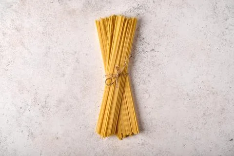 Uncooked raw bunch of spaghetti on grey textured background Stock Photos