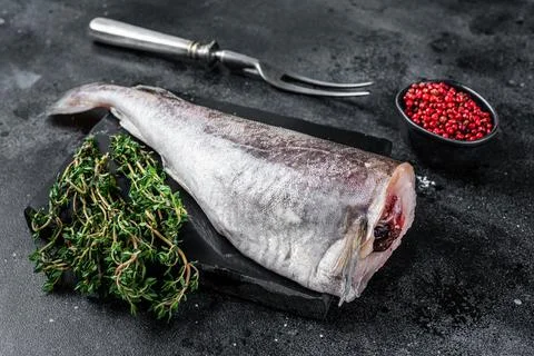 Uncooked Raw cod whole fish on marble board with thyme. Black background. Top Stock Photos