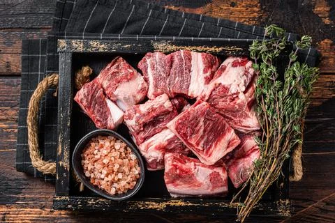 Uncooked Raw diced cubes of lamb meat in wooden tray with salt and thyme. Wooden Stock Photos