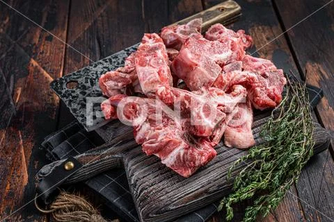 Photograph: Uncooked Raw meat diced for stew on a butcher board. Dark