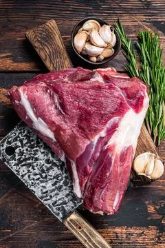 Uncooked Raw mutton lamb thigh on butcher board with meat cleaver. Dark wooden Stock Photos