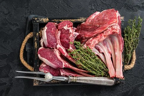 Uncooked Raw Rack and lamb, mutton rib chops in a wooden tray. Black background Stock Photos