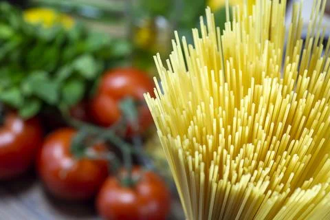 Uncooked raw spaghetti pasta with vegetables in the background Stock Photos