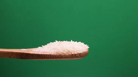 Uncooked raw white long grain rice pour drop fall on wooden spoon spin rota.. Stock Footage 261982853