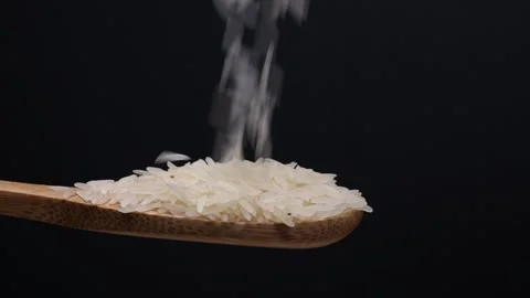 Uncooked raw white long grain rice pour drop fall on wooden spoon spin rota.. Stock Footage 261982854