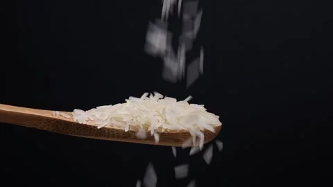 Uncooked raw white long grain rice pour drop fall on wooden spoon spin rota.. Stock Footage 261982962