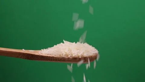 Uncooked raw white long grain rice pour drop fall on wooden spoon spin rota.. Stock Footage 261983087