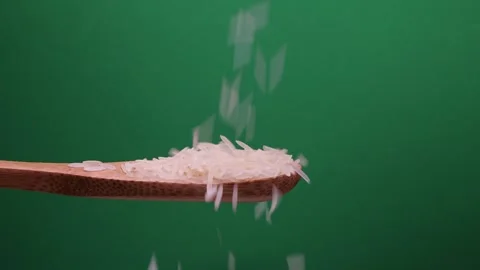 Uncooked raw white long grain rice pour drop fall on wooden spoon spin rota.. Stock Footage 261983146
