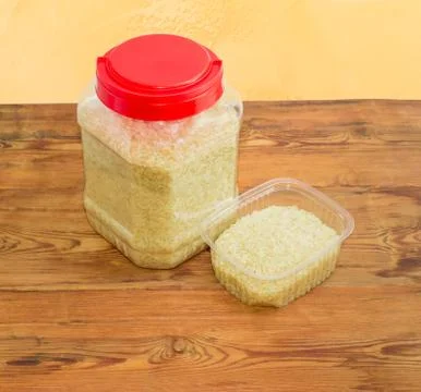 Uncooked rice in two different big and small plastic containers Stock Photos