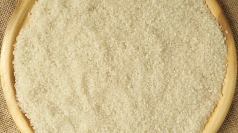 Uncooked white rice grains rotating in a wooden bowl Stock Footage 335560163