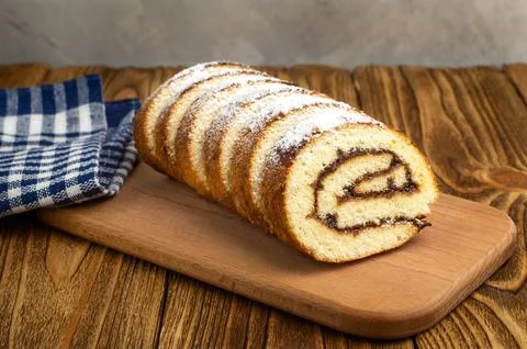 Uncut biscuit roll with fruit jam and powdered sugar on a cutting board, on.. Stock Photos