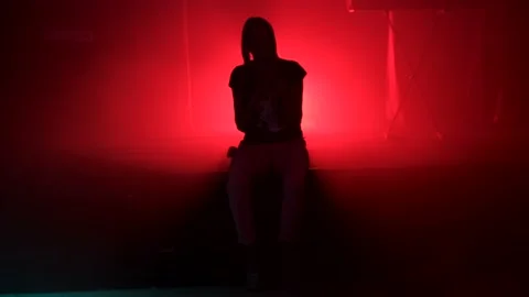 Undefined female person silhouette sitting along on floor stage Stock Footage 145364853