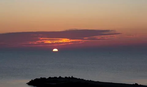 Under the attractive clouds, the sun rises above the sea. Stock Photos