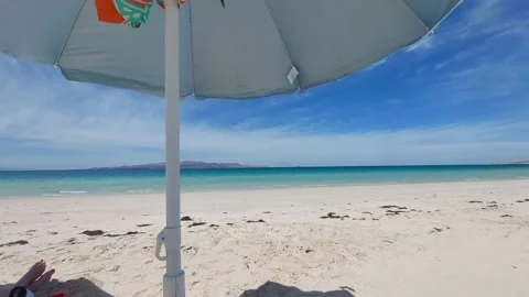 Under beach umbrella sandy blue water bree Stock Footage 172424253
