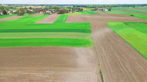 Under a bright spring sky, patchwork green and brown farm fields spread toward Stock Footage 347017484