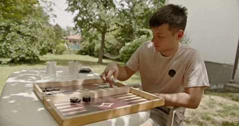 Under the bright sun, two people play backgammon outdoors, savoring a relaxing Stockbeeldmateriaal 281967307