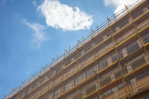 Under construction. Building construction with scaffolding, blue sky backgrou Stock Photos